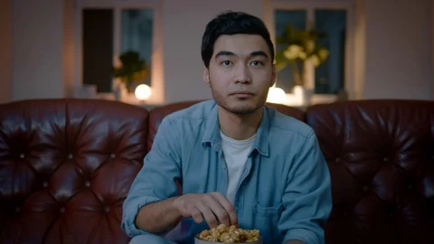 Asian adult male person eating popcorn and watching TV on big screen in the bed. Stock Footage