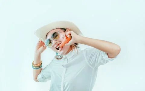 Asian adult wearing a sun hat and eating carrots on  white background Stock Photos