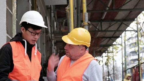 Asian apprentice engineer at work on construction site with senior manager Stock Footage 82657247