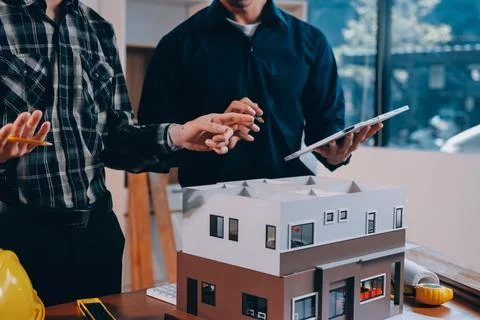 Asian architect and engineer team checking architectural house model using .. Stock Photos
