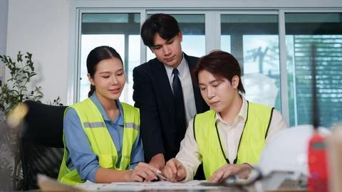 Asian architects and engineer analyzing building blueprints during office Stock Photos