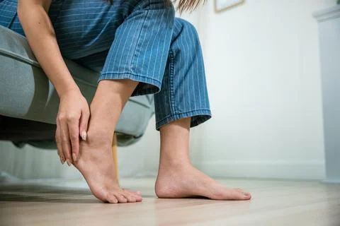 Asian beautiful female problems with foot at home Fotos de archivo