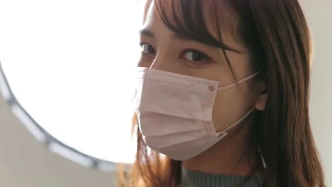 Asian beautiful model covers her face with a mask in front of light. Slow-mo Stock Footage 221018852