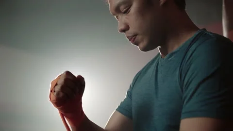 Asian boxer wraps his hand before wearing his gloves to practice punches Stock Footage 152068331