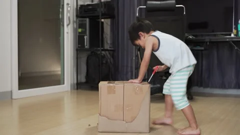 Asian boy about 4 years old opening package box Stock Footage 131132426
