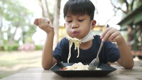 Asian boy about 5 years old with face mask under the chin eating spaghetti Video stock 152290535