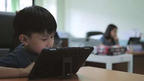 Asian boy addictive watching tablet while his mother working. Stock Footage 197365619