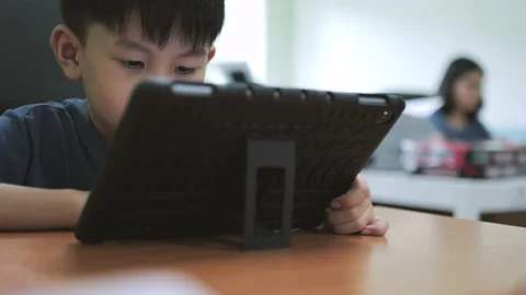 Asian boy addictive watching tablet while his mother working. Stock Footage 221994565