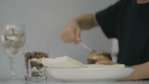 Asian boy adding peanut butter spread to sliced bread. Stock Footage 157057429
