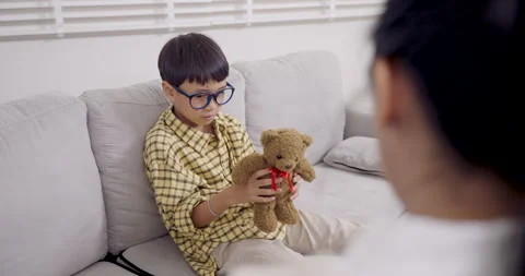 Asian boy with ADHD plays slowly with teddy bear on sofa during slowmotion Stock Footage 319220564