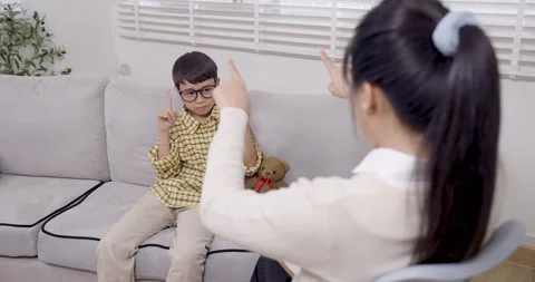 Asian boy with adhd sitting on sofa during interactive therapy activity raising Video stock 319221694