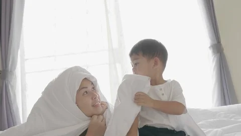 The asian boy and his mother are playing together on the bed . Stock Footage