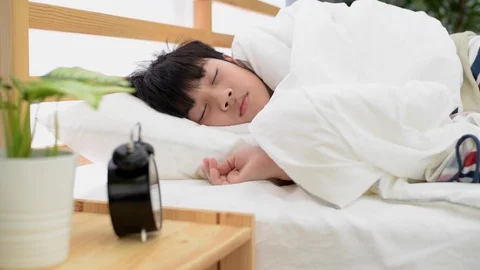 Asian Boy Asleep In Bed Woken By Alarm Clock. 库存影片 87674178