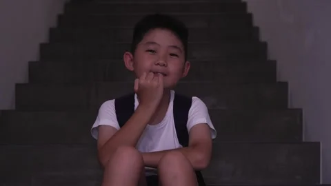 Asian boy biting fingernails, stressing over academic result in the staircase 4k Stock Footage 300075695