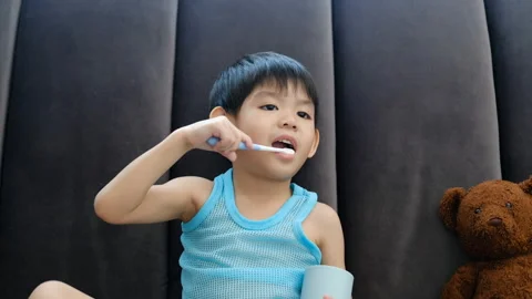 Asian boy brushing his teeth on the living room Stock Footage 252079067