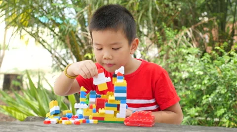 Asian boy build plastic block on wooden table in park Stock Footage 63037682