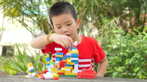 Asian boy build plastic block on wooden table in park Stock Footage 63043782