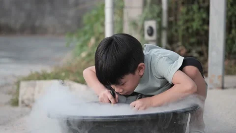 An Asian boy does an experiment with dry Ice. Video stock 171094296