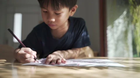Asian boy doing his homework, drawing and painting picture Stock Footage 147336946