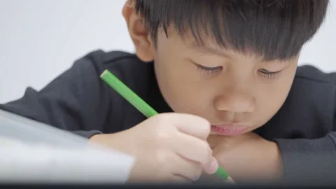 Asian boy doing homework with a boring and tired expression. Stock Footage 156603821