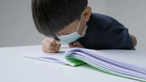 Asian boy doing homework by writing letter on the book. Video stock 154347843