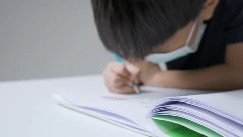 Asian boy doing homework by writing letter on the book. Stock Footage 165681798