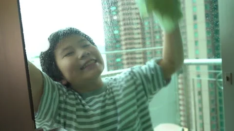 Asian boy doing housework to clean the glass door and window at home 4K Stock Footage 139567128