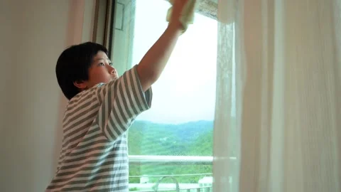 Asian boy doing housework to clean the glass door and window at home 4K Stock Footage 139567130