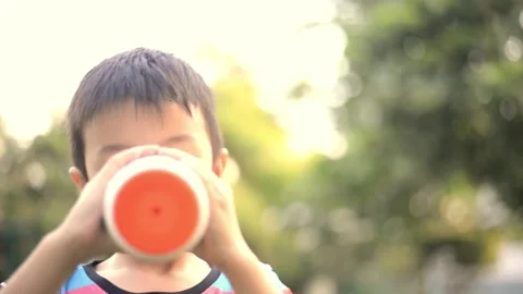 Asian boy drinking  water from flask in the pak Stockbeeldmateriaal 250370505