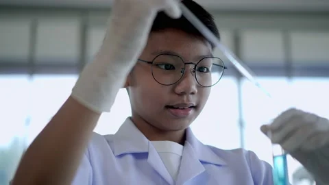 Asian boy drop blue liquid during learn chemistry at laboratory Stock Footage 201361870