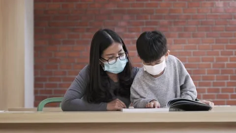 Asian boy with face mask reading the book with his mother Video stock 148642892