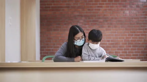 Asian boy with face mask reading the book with his mother Video stock 158289470