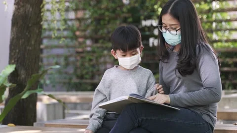 Asian boy with face mask reading the book with his mother Stock Footage 160277779