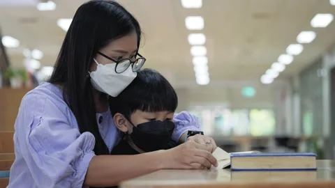 Asian boy with face mask reading the book with his mother Stock Footage 164524534