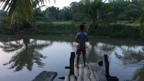 An Asian boy feeding fish on the pool Stockbeeldmateriaal 89952422