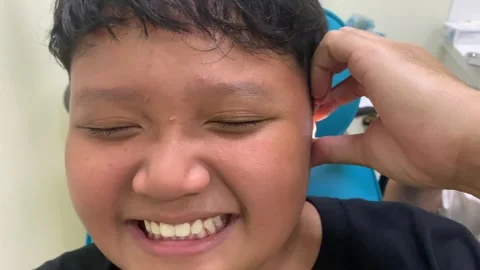 Asian boy felt ticklish when his ears were cleaned by the doctor. Stock Footage 333456950