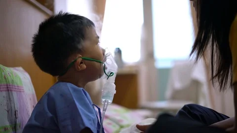 Asian boy is given inhaler containing medicine to stop coughing by his mother Video stock 95184731