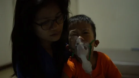 Asian boy is given inhaler containing medicine to stop coughing by his mother Stock Footage 117264869