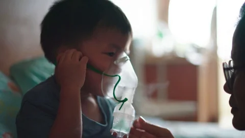 Asian boy is given inhaler containing medicine to stop coughing by his mother Video stock 117264935