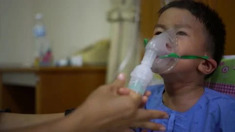 Asian boy is given inhaler containing medicine to stop coughing by his mother Stock Footage 151249313