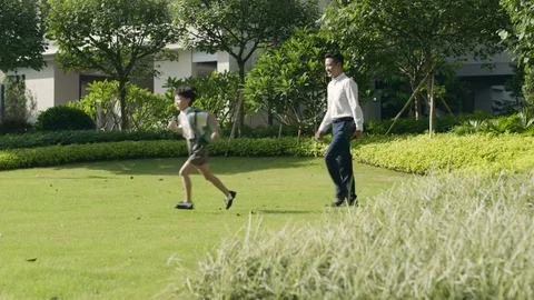 Asian boy going through garden to school with his father Stock Footage 78198993