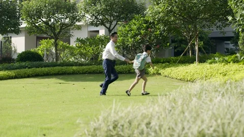 Asian boy going through garden to school with his father Video stock 78205837