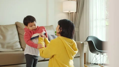 Asian Boy having fun while mother helping to get dressed Stock Footage 261123525