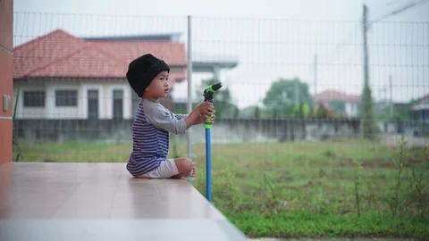 Asian boy help watering grass yard Stock Footage 98344397
