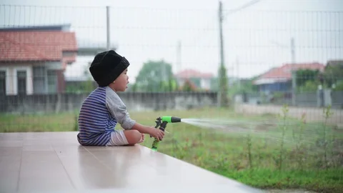 Asian boy help watering grass yard Stock Footage 117267601