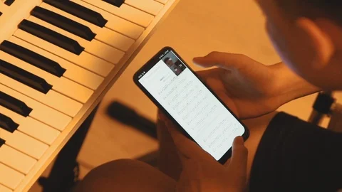 Asian boy learning piano by himself by looking up notes on the smartphone Stock-Footage 107936811