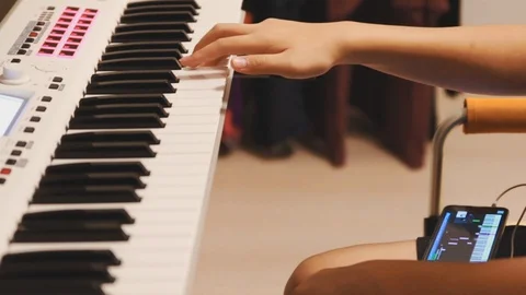 Asian boy learning piano by himself by following a video on his smartphone Stock Footage 107936879