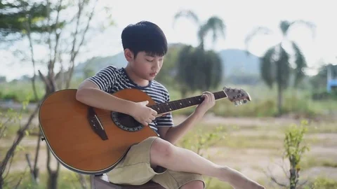 Asian boy learning to play the guitar Stock Footage 83052280