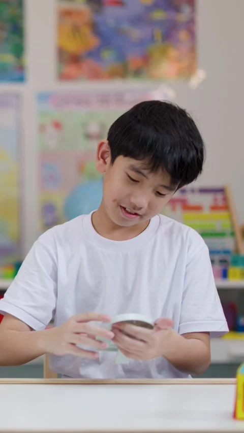 Asian Boy Learning to Tell Time With Toy Clock in Classroom Vídeo Stock 321723535