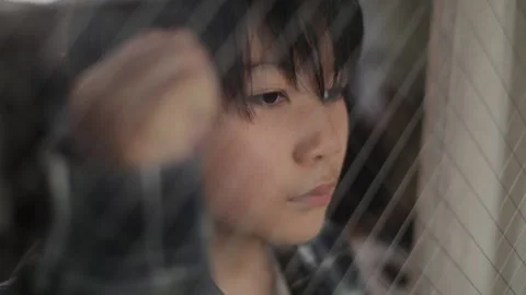 Asian boy looks out of the window with strong emotion. Stock Footage 224289560